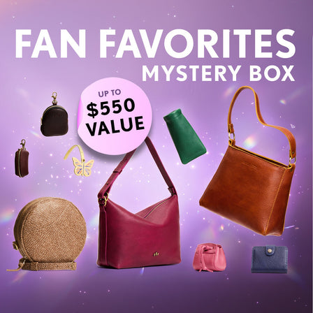 Promotional graphic for a 'Fan Favorites Mystery Box' featuring a collection of shoulder bags, crossbodies, wallets, and small goods. Set against a purple sparkly background with a pink badge indicating up to $550 value.