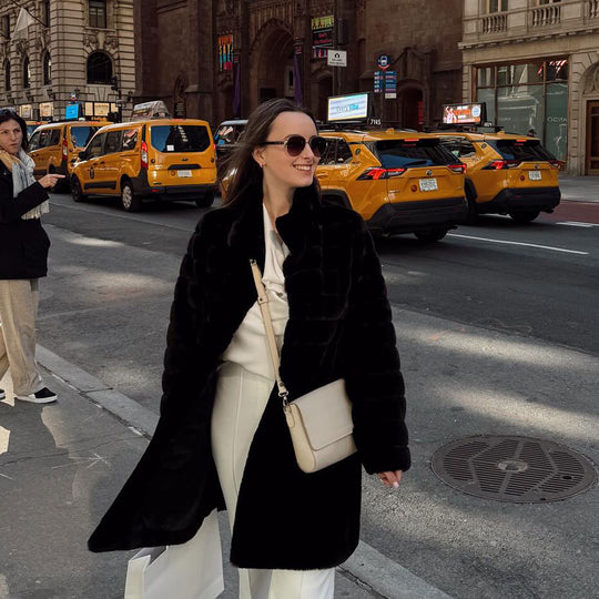 person standing in front of taxis wearing a PLG bag