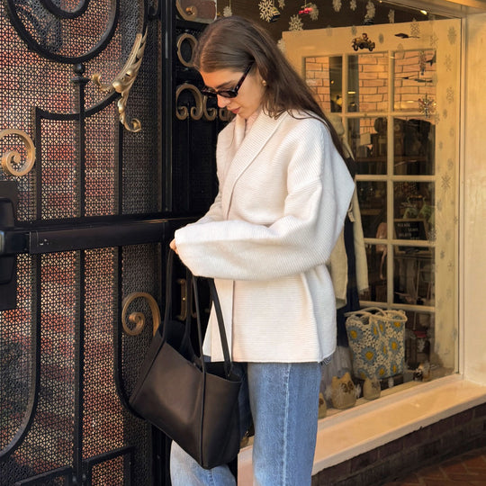 person standing in a white coat with a black PLG tote