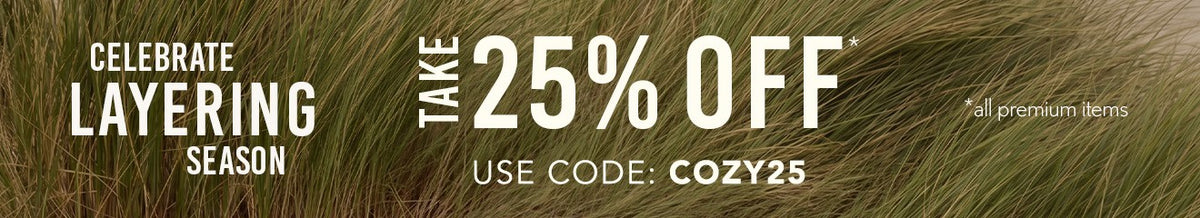 A tall grassy background with Text: Celebrate Layering season. Take 25% off* | Use Code: COZY25 *all premium items.