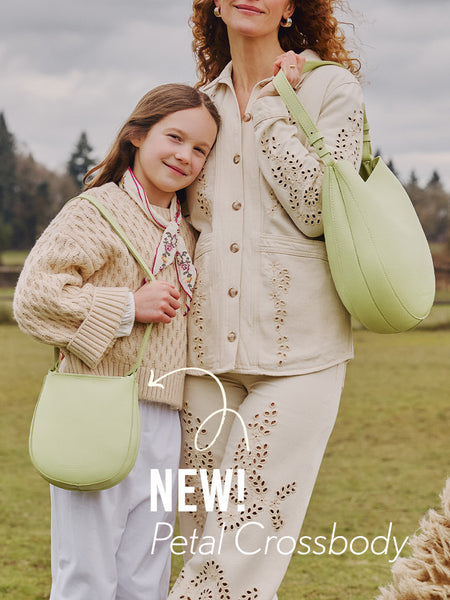 An adult and a child standing outdoors with the Olivia Shoulder bag and Petal Crossbody in Shadow Lime, featuring 'NEW! Petal Crossbody' text.