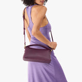 Plum | Model holding a plum colored bowler style hand bag 