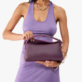 Plum | Model holding a plum colored bowler style hand bag 