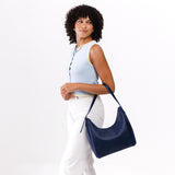 Cobalt Medium | Model holding u-shaped, flat-bottomed leather shoulder bag with adjustable strap
