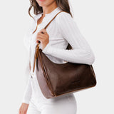 Coldbrew Medium | Model holding u-shaped, flat-bottomed leather shoulder bag with adjustable strap