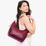 Orchid Medium | Model holding u-shaped, flat-bottomed leather shoulder bag with adjustable strap