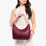 Orchid Medium | Model holding u-shaped, flat-bottomed leather shoulder bag with adjustable strap