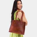 Nutmeg Medium | Model holding leather tote bag with interior snap key loop VARIANT2