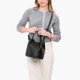 Black Large | Model holding symmetrical bucket bag with handle, latch closure, and removable crossbody strap
