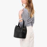 Black Large | Model carrying symmetrical bucket bag with handle, latch closure, and removable crossbody strap
