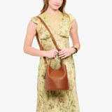 Honey Large | Model wearing symmetrical bucket bag with handle, latch closure, and removable crossbody strap