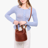 Nutmeg Large | Model wearing symmetrical bucket bag with handle, latch closure, and removable crossbody strap