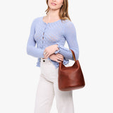 Nutmeg Large | Model carrying symmetrical bucket bag with handle, latch closure, and removable crossbody strap