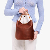 Nutmeg Large | Model holding symmetrical bucket bag with handle, latch closure, and removable crossbody strap