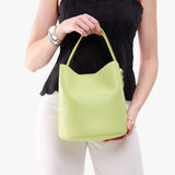 Shadow Lime Large | Model holding symmetrical bucket bag with handle, latch closure, and removable crossbody strap