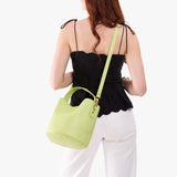 Shadow Lime Large | Model wearing symmetrical bucket bag with handle, latch closure, and removable crossbody strap