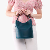 Westward Blue Large | Model holding symmetrical bucket bag with handle, latch closure, and removable crossbody strap