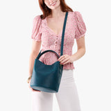 Westward Blue Large | Model holding symmetrical bucket bag with handle, latch closure, and removable crossbody strap