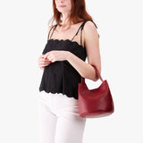 Chili Red Small | Model carrying symmetrical bucket bag with handle, latch closure, and removable crossbody strap