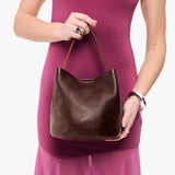 Coldbrew Small | Model holding symmetrical bucket bag with handle, latch closure, and removable crossbody strap