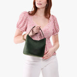 Evergreen Small | Model holding symmetrical bucket bag with handle, latch closure, and removable crossbody strap