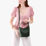 Evergreen Small | Model holding symmetrical bucket bag with handle, latch closure, and removable crossbody strap