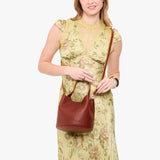 Nutmeg Small | Model wearing symmetrical bucket bag with handle, latch closure, and removable crossbody strap