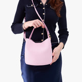 Pinkaboo Small | Model holding symmetrical bucket bag with handle, latch closure, and removable crossbody strap