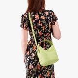 Shadow Lime Small | Model wearing symmetrical bucket bag with handle, latch closure, and removable crossbody strap