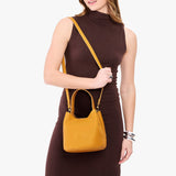 Sunshine Small | Model wearing symmetrical bucket bag with handle, latch closure, and removable crossbody strap