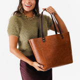 Meadow Classic | Model holding large zipper leather tote bag with sturdy bridle handles and front pocket