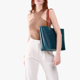 Westward Blue Classic | Model holding large leather tote bag with sturdy bridle handles and front pocket
