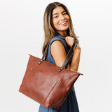 Nutmeg Zipper | Model holding large zipper leather tote bag with sturdy bridle handles and front pocket