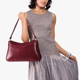 Cabernet Large | Model holding a bean shaped shoulder bag with a zipper closure