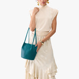 Aquarius Small | Model wearing matching white shirt and skirt carrying petite bucket shaped tote bag with matching leather handles
