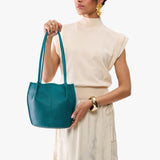 Aquarius Small | Model wearing matching white shirt and skirt carrying petite bucket shaped tote bag with matching leather handles