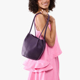 Empire Small | Model wearing sleeveless pink dress carrying petite bucket shaped tote bag with matching leather handles