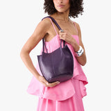 Empire Small | Model wearing sleeveless pink dress holding petite bucket shaped tote bag with matching leather handles