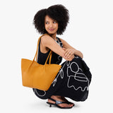 Sunshine Large | Model wearing black dress and carrying wide bucket shaped tote bag with matching leather handles