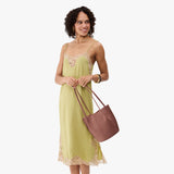 Sunkissed Small | Model wearing sleeveless light green dress holding petite bucket shaped tote bag with matching leather handles