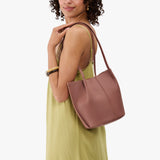 Sunkissed Small | Model wearing sleeveless light green dress carrying petite bucket shaped tote bag with matching leather handles