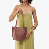 Sunkissed Small | Model wearing sleeveless light green dress holding petite bucket shaped tote bag with matching leather handles