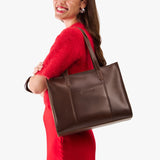 Chocolate Brown East/West | Model wearing structured wide tote bag with overlapping panels and crossbody strap