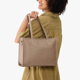 Stone East/West | Model holding structured wide tote bag with overlapping panels and crossbody strap