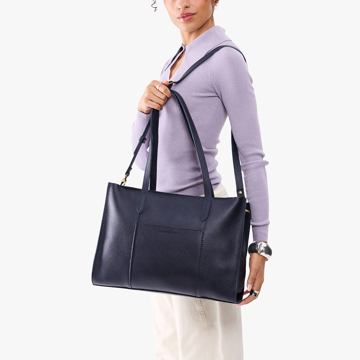 Night Owl*Oversized East/West | Model holding structured wide tote bag with overlapping panels and crossbody strap