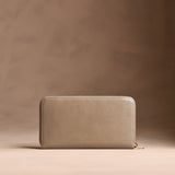 Satine | Full zip around wallet with a strap on a brown background
