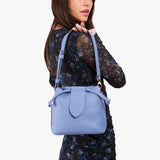 Aster Small | Model holding symmetrical leather bag with leather drawstring closure and adjustable shoulder strap