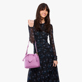 Calla Lily Small | Model holding symmetrical leather bag with leather drawstring closure and adjustable shoulder strap