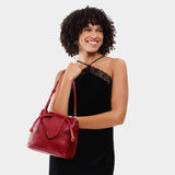 Chili Red Small | Model holding symmetrical leather bag with leather drawstring closure and adjustable shoulder strap