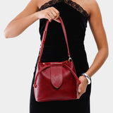 Chili Red Small | Model holding symmetrical leather bag with leather drawstring closure and adjustable shoulder strap